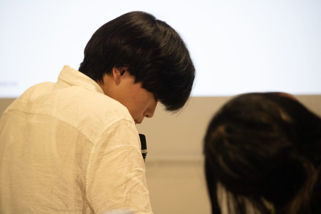 写真。発表する少年の後ろ姿。