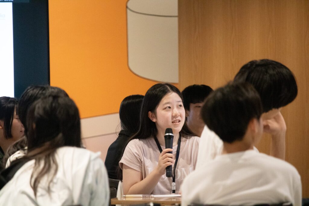 写真。マイクを持ち、発表する少女。