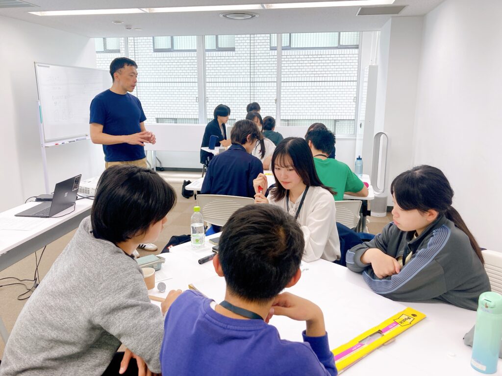 写真。会場の中で講義をする濱代表。