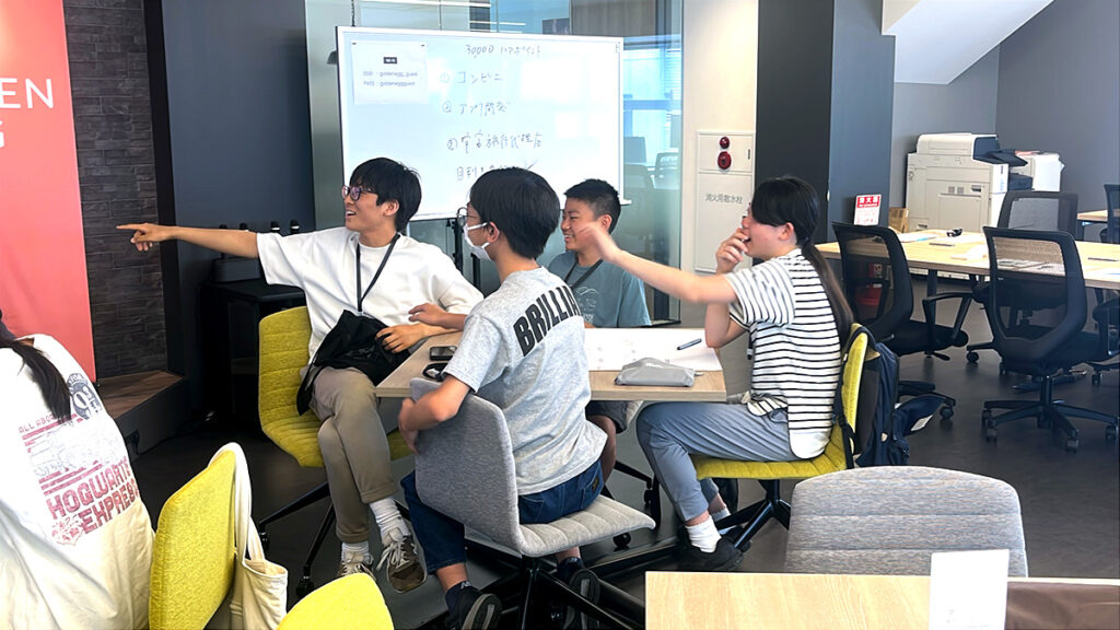 写真。何かを見て笑い合う少年少女4人チーム。楽しそうな様子が伝わってくる。