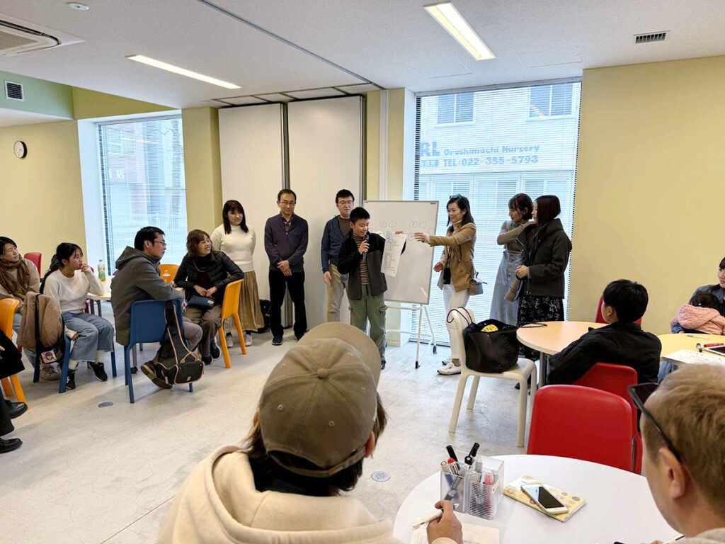 写真。大人の前でビジネスプレゼンを行う少年。