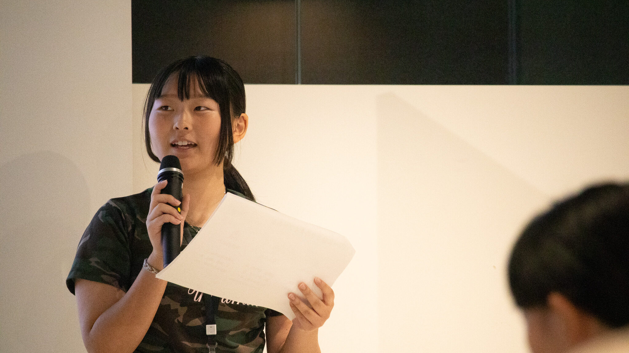写真。マイクを手にプレゼンする少女。