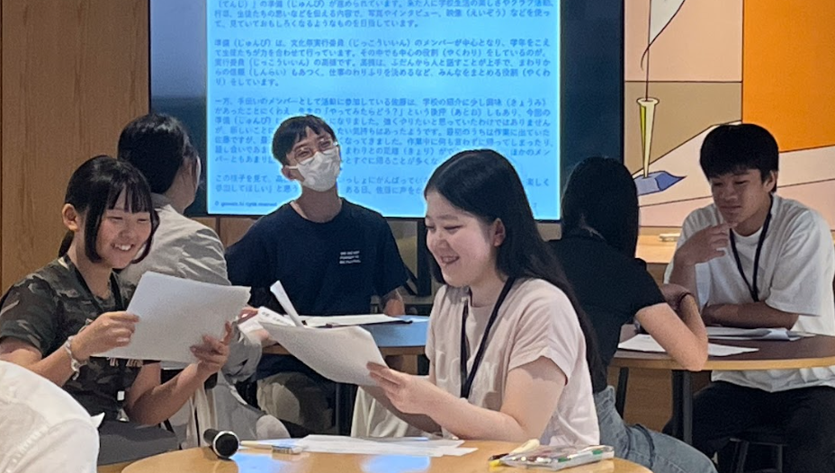 写真。にこやかにプリントを読む受講生たち。