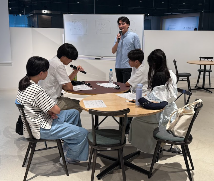 写真。マイクを持って発表する受講生。